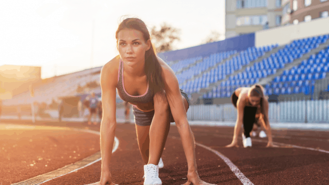 Women sprinters at starting position ready for race on racetrack