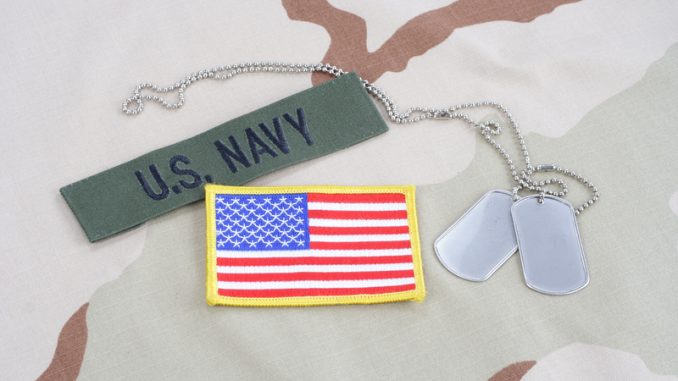 US NAVY branch tape with dog tags and flag patch on desert camouflage uniform background