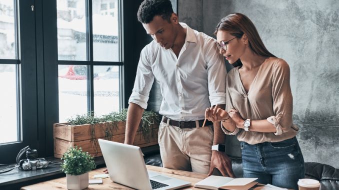 Young confident business people using computer and smiling while working in the office