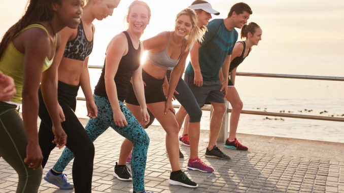 Running club members training together in morning under a bridge.