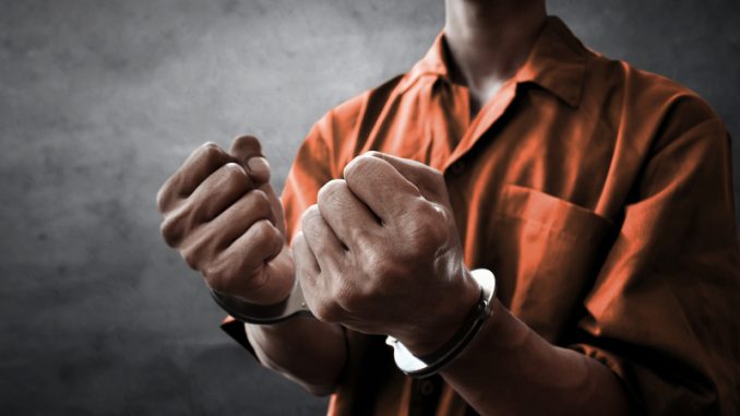 Arrested man in handcuffs in prison