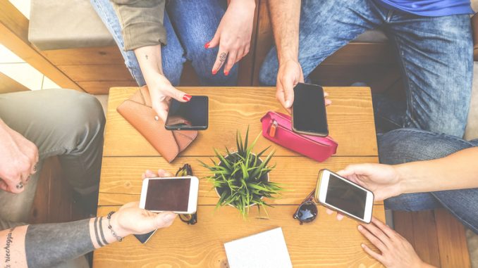 Top view of a group of hipster friends sitting in a bar cafe using mobile smart phone - New young generation trend