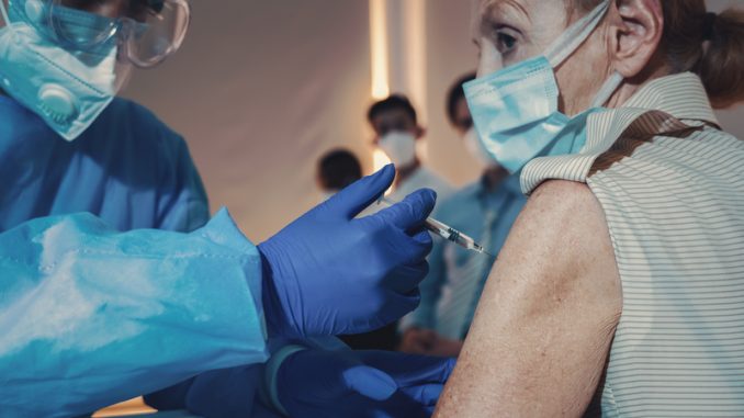 Caucasian senior women having virus vaccine injection by medical nurse at hospital for coronavirus covid-19 immunization.