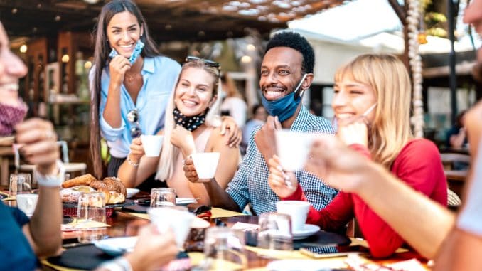 People having fun together at cafeteria with face masks