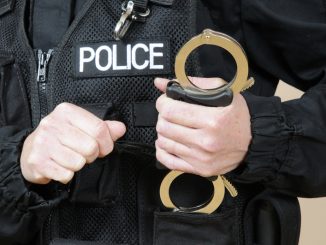 Uniformed police officer holding handcuffs