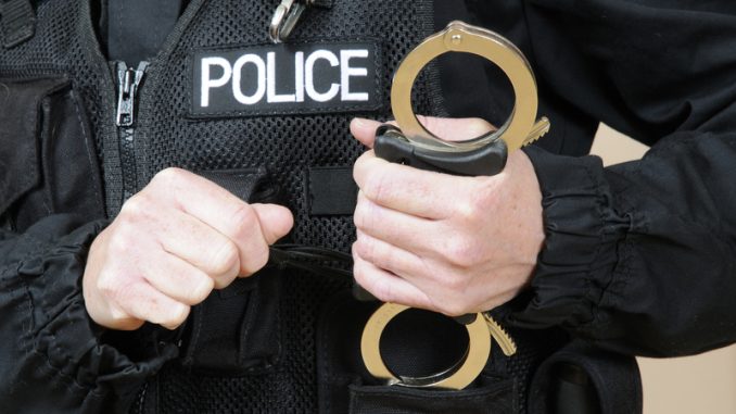 Uniformed police officer holding handcuffs