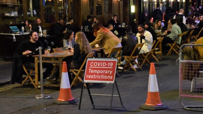 Outdoor street seating at bars and restaurants with COVID-19 Temporary Restrictions sign